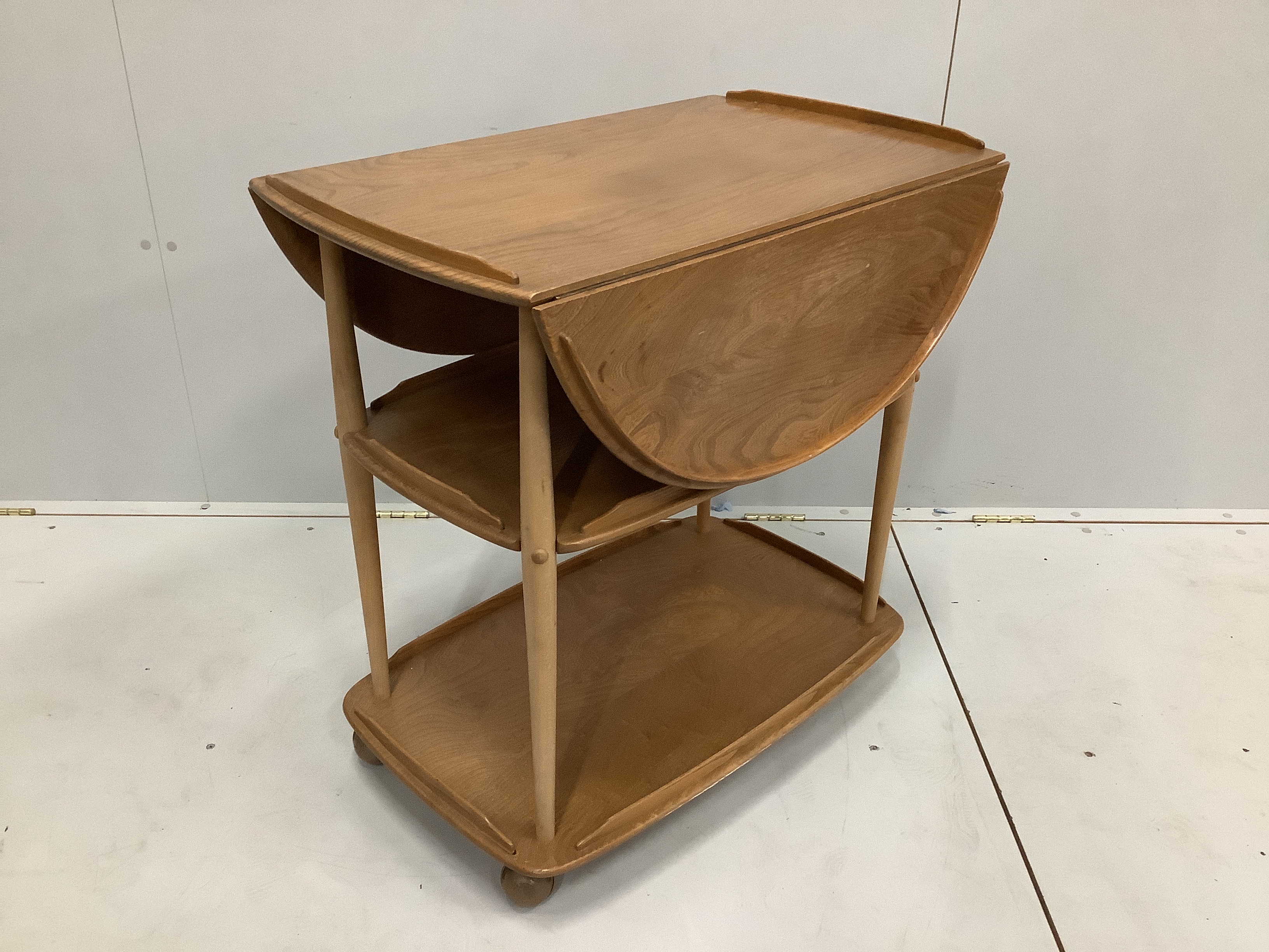 An Ercol elm and beech three tier drop flap tea trolley, width 72cm, depth 46cm, height 76cm